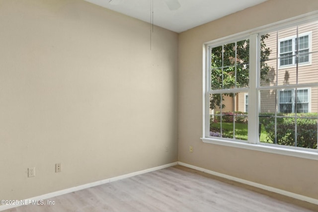 unfurnished room featuring baseboards, a wealth of natural light, a ceiling fan, and light wood finished floors