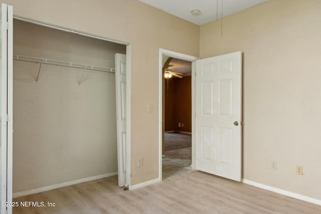 unfurnished bedroom featuring a closet, baseboards, wood finished floors, and attic access