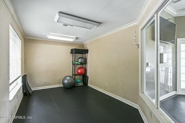exercise room featuring baseboards, ornamental molding, visible vents, and plenty of natural light