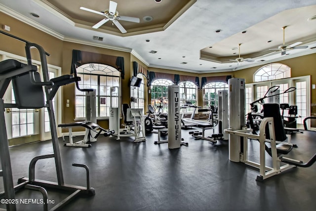exercise room featuring a raised ceiling, visible vents, crown molding, and ceiling fan