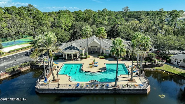 exterior space featuring a community pool, a water view, fence, and a patio area