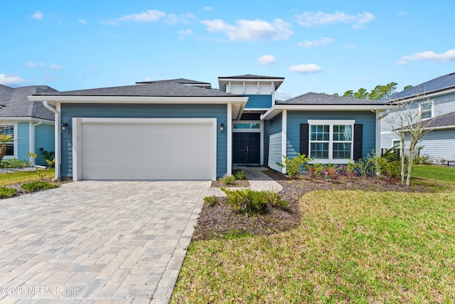 view of front facade featuring a front yard, decorative driveway, and an attached garage