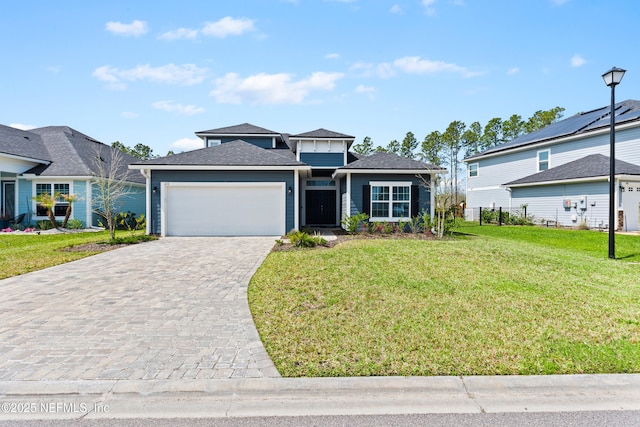 view of front of home with a front yard, decorative driveway, and a garage
