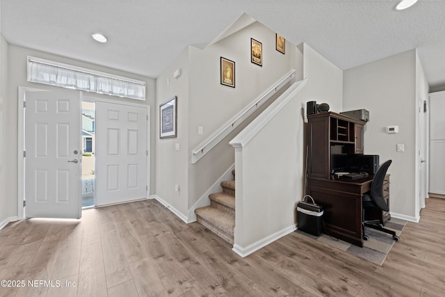 foyer featuring stairway, baseboards, and light wood finished floors