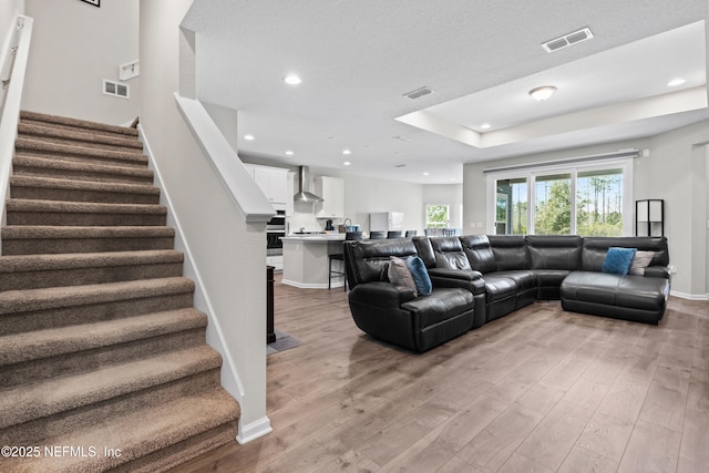 living room featuring stairs, light wood-style flooring, and visible vents