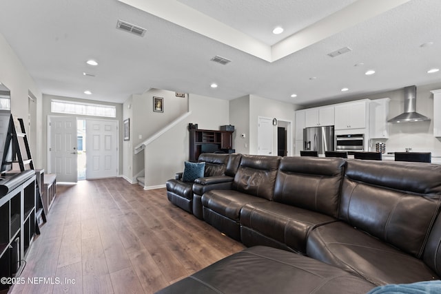 living room featuring recessed lighting, hardwood / wood-style flooring, stairs, and visible vents