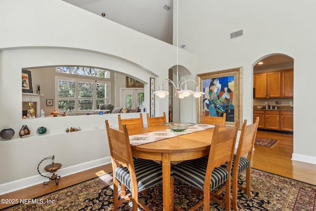 95062 Mackinas Cir, Fernandina Beach, FL 32034 - dining space with light wood-style floors, a high ceiling, baseboards, visible vents, and arched walkways