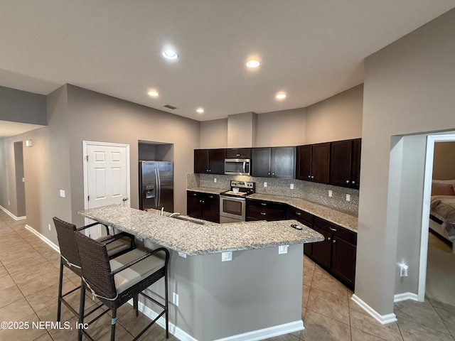 3118 Steeple Pine Ct, Middleburg, FL 32068 - kitchen featuring appliances with stainless steel finishes, light tile patterned floors, a kitchen bar, backsplash, and a large island with sink