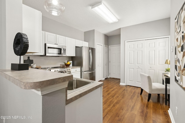 542 Southbranch Dr, Saint Johns, FL 32259 - kitchen with dark wood-style flooring, a peninsula, white cabinetry, and stainless steel appliances
