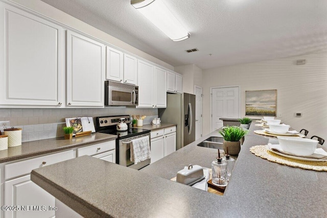 kitchen featuring white cabinetry, appliances with stainless steel finishes, backsplash, and visible vents