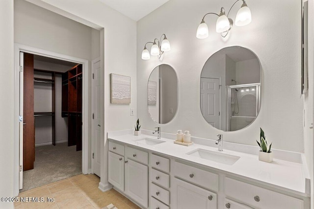full bath with a shower stall, double vanity, a spacious closet, and a sink