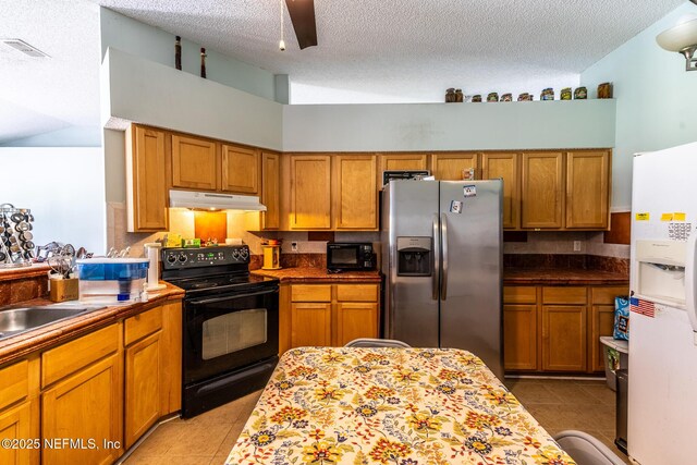 9587 Ford Rd, Bryceville, FL 32009 - kitchen with brown cabinets, under cabinet range hood, light tile patterned floors, black appliances, and ceiling fan
