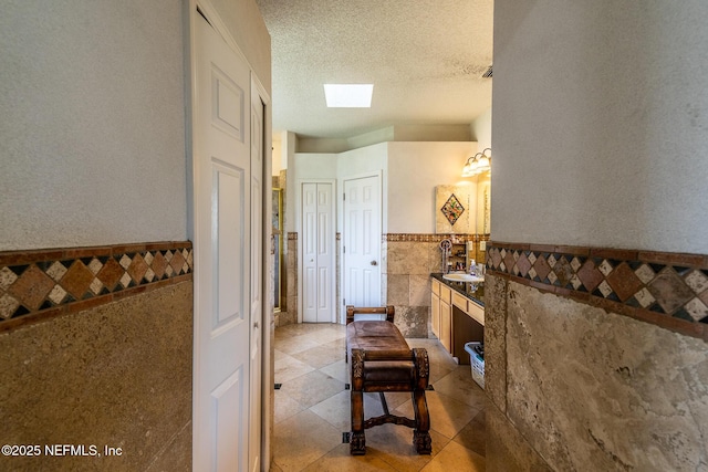 9587 Ford Rd, Bryceville, FL 32009 - corridor featuring a sink, a skylight, a textured ceiling, wainscoting, and tile walls