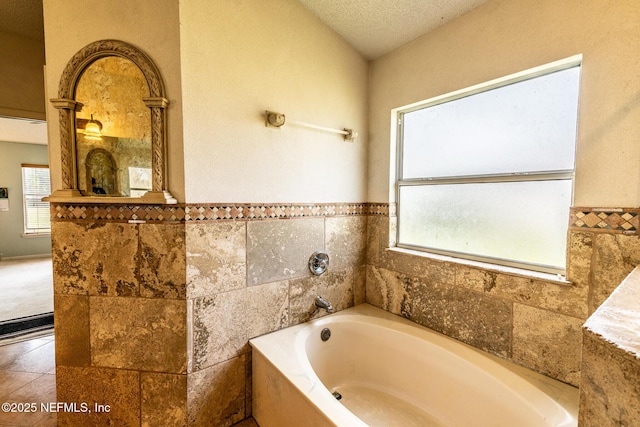 9587 Ford Rd, Bryceville, FL 32009 - full bathroom with a wainscoted wall, a garden tub, a textured ceiling, tile patterned flooring, and tile walls