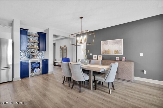 1021 Oakland Hills Ave, Middleburg, FL 32068 - dining area featuring a chandelier, a bar, beverage cooler, light wood-style flooring, and baseboards