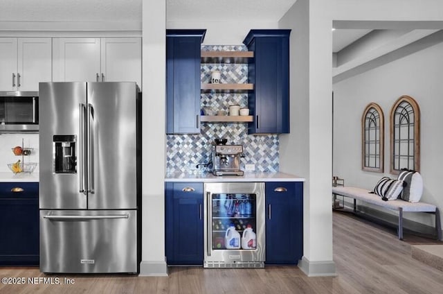 1021 Oakland Hills Ave, Middleburg, FL 32068 - bar with wine cooler, wood finished floors, appliances with stainless steel finishes, baseboards, and decorative backsplash