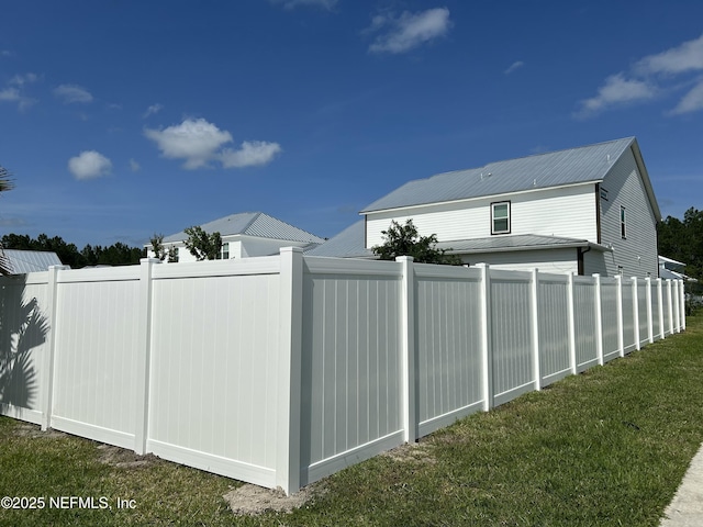 view of property exterior with metal roof, a lawn, and fence