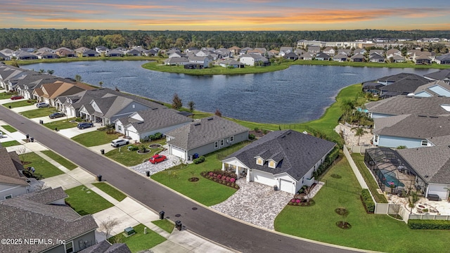 aerial view at dusk with a water view and a residential view