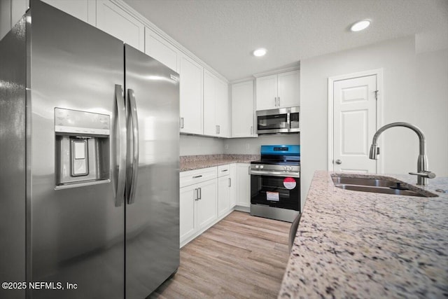 8910 Free Ave, Jacksonville, FL 32211 - kitchen with light wood-style floors, a sink, white cabinetry, and stainless steel appliances