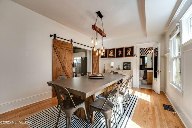 2855 Post St, Jacksonville, FL 32205 - dining space featuring baseboards, a barn door, light wood finished floors, and visible vents