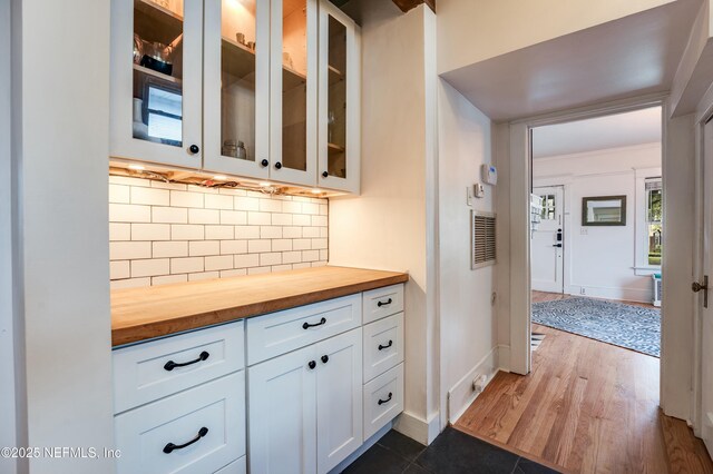 2855 Post St, Jacksonville, FL 32205 - kitchen with butcher block countertops, dark wood-type flooring, backsplash, white cabinets, and glass insert cabinets