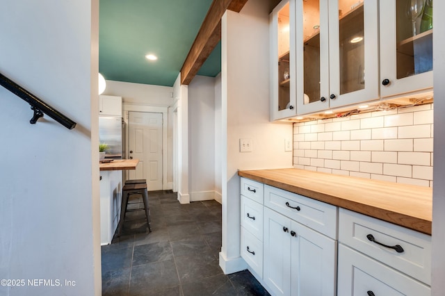 2855 Post St, Jacksonville, FL 32205 - kitchen with wooden counters, baseboards, glass insert cabinets, white cabinetry, and backsplash