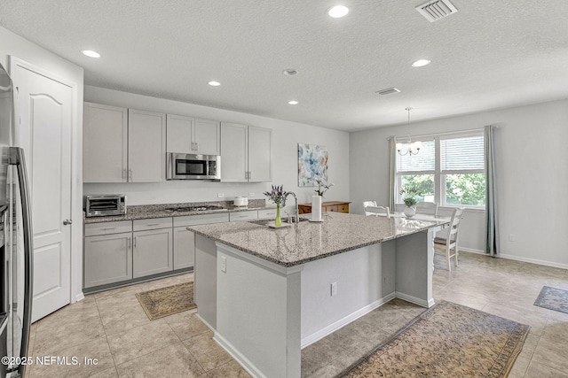 12424 Shady Bridge Trl, Jacksonville, FL 32258 - kitchen featuring light stone countertops, visible vents, a sink, stainless steel appliances, and a center island with sink