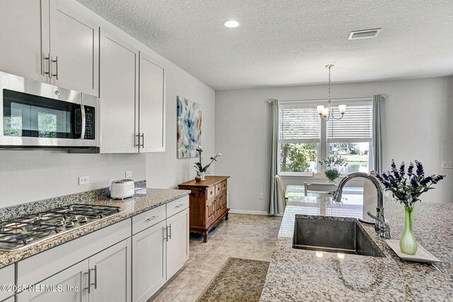 12424 Shady Bridge Trl, Jacksonville, FL 32258 - kitchen with a chandelier, light stone countertops, visible vents, appliances with stainless steel finishes, and a sink