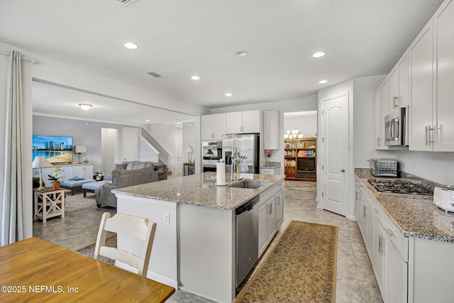 12424 Shady Bridge Trl, Jacksonville, FL 32258 - kitchen with white cabinets, appliances with stainless steel finishes, light stone counters, a sink, and a center island with sink