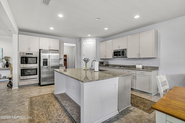 12424 Shady Bridge Trl, Jacksonville, FL 32258 - kitchen with light stone countertops, visible vents, appliances with stainless steel finishes, a kitchen island with sink, and a sink