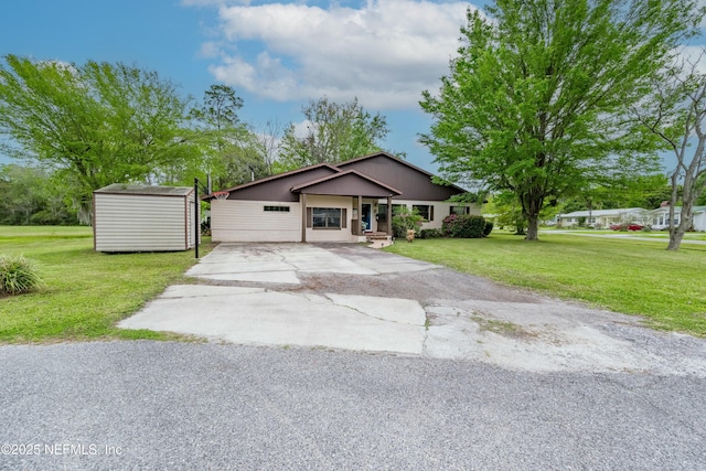 view of front of home featuring driveway, an outbuilding, a storage unit, and a front yard