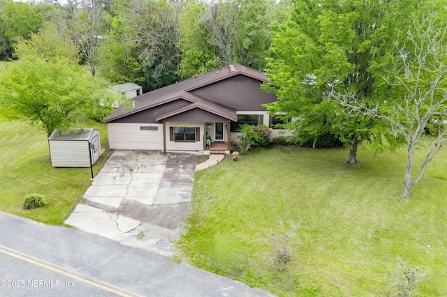 view of front facade with an outdoor structure, a storage unit, concrete driveway, and a front yard