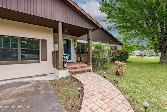 property entrance with a lawn and covered porch