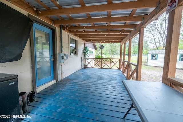 wooden terrace with a storage unit and an outbuilding