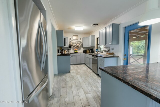 kitchen featuring visible vents, ornamental molding, stainless steel appliances, wood finish floors, and a sink