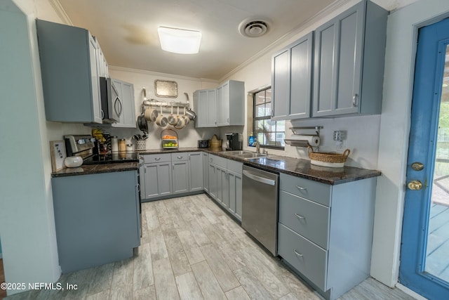 kitchen with crown molding, a sink, light wood-type flooring, stainless steel appliances, and visible vents