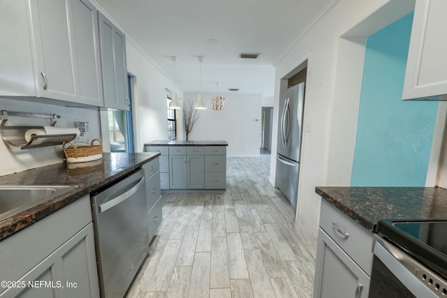 kitchen featuring ornamental molding, stainless steel appliances, light wood-style floors, and visible vents