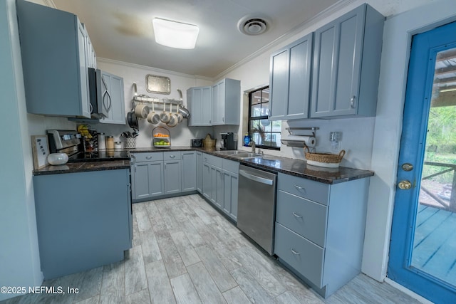 kitchen featuring visible vents, crown molding, light wood finished floors, stainless steel appliances, and a sink