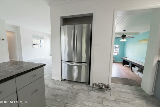 kitchen featuring freestanding refrigerator, dark stone countertops, wood finish floors, ceiling fan, and ornamental molding