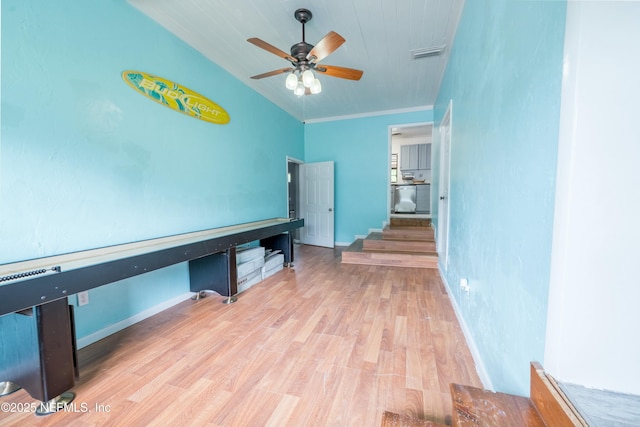 interior space with a ceiling fan, wood finished floors, baseboards, and visible vents