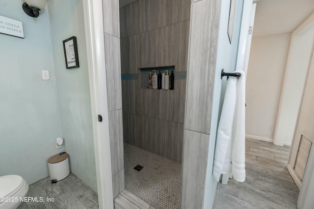 bathroom with visible vents, toilet, wood tiled floor, and walk in shower