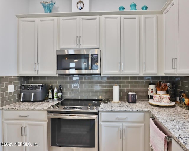 11466 Leatherback Ct, Jacksonville, FL 32256 - kitchen with white cabinetry, light stone countertops, decorative backsplash, and stainless steel appliances