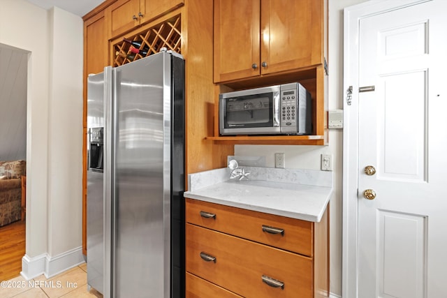 819 Lasalle St Unit 819, Jacksonville, FL 32207 - kitchen with baseboards, appliances with stainless steel finishes, light stone counters, brown cabinetry, and light tile patterned floors