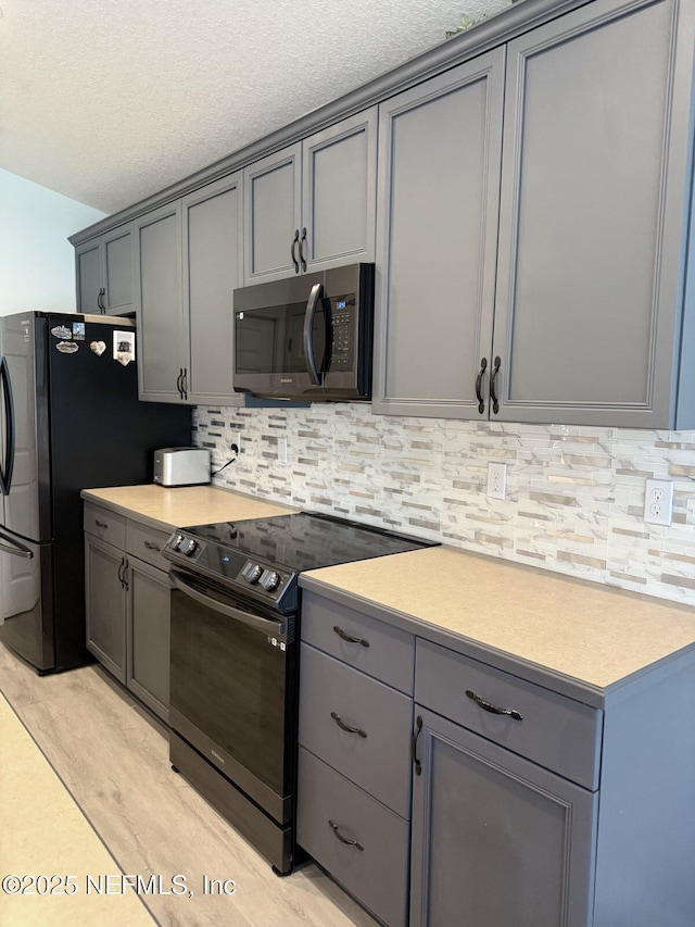 200 Nottingham Dr W, Saint Johns, FL 32259 - kitchen with stainless steel appliances, gray cabinets, light countertops, backsplash, and a textured ceiling
