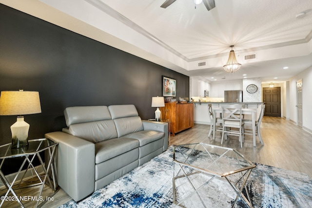 1478 Riverplace Blvd Unit 1103, Jacksonville, FL 32207 - living room featuring a tray ceiling, visible vents, ceiling fan with notable chandelier, and light wood finished floors