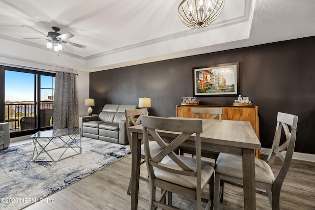 1478 Riverplace Blvd Unit 1103, Jacksonville, FL 32207 - dining space featuring ceiling fan with notable chandelier, a tray ceiling, baseboards, and wood finished floors