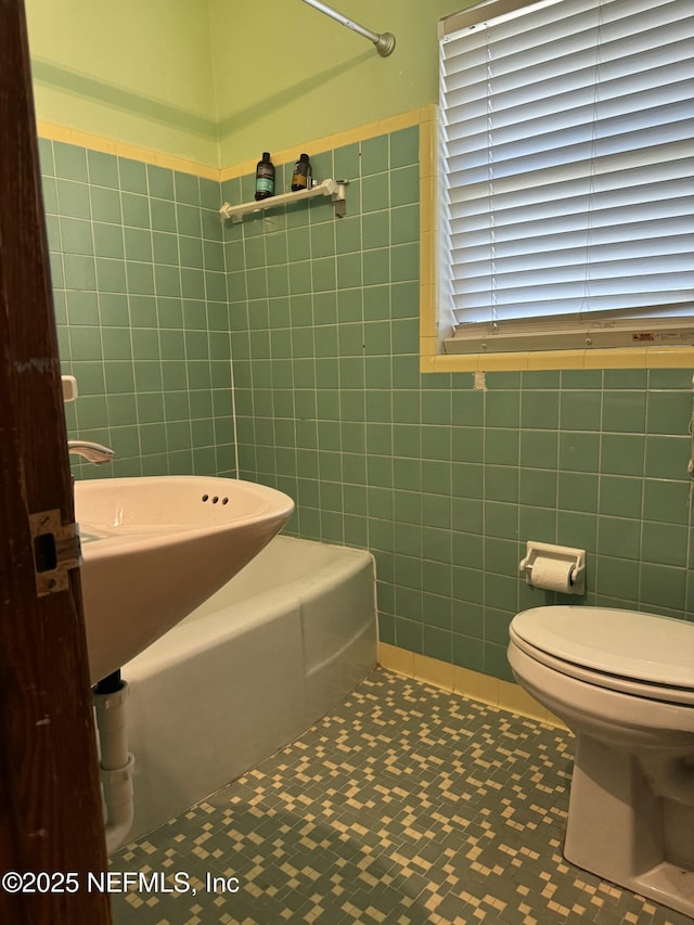 1103 Palm Cir, Jacksonville Beach, FL 32250 - full bath featuring tile walls, tile patterned floors, a washtub, and toilet