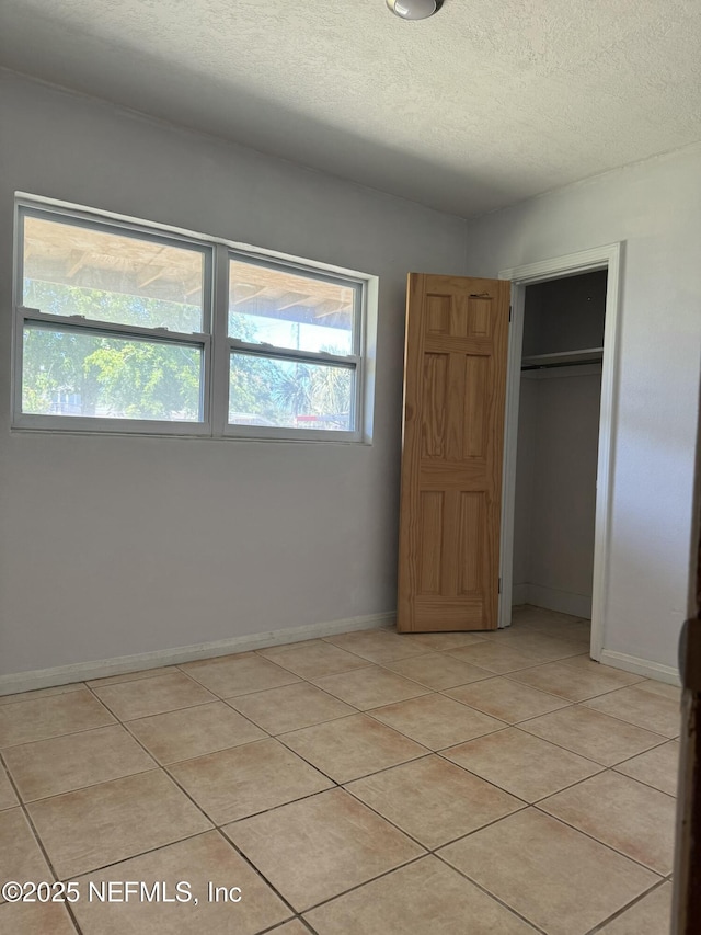 1103 Palm Cir, Jacksonville Beach, FL 32250 - unfurnished bedroom with baseboards, a textured ceiling, a closet, and light tile patterned floors