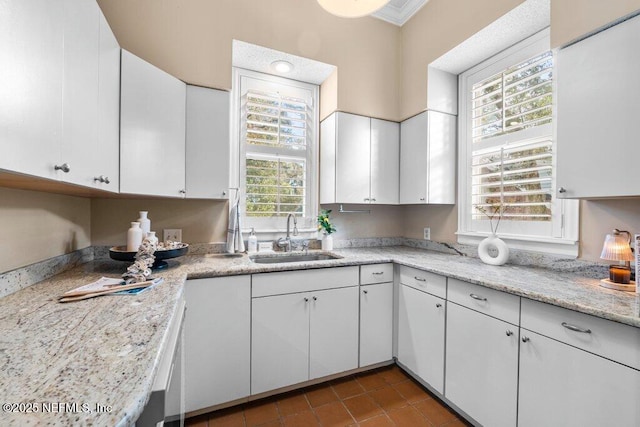 kitchen featuring tile patterned floors, white cabinets, ornamental molding, and a sink