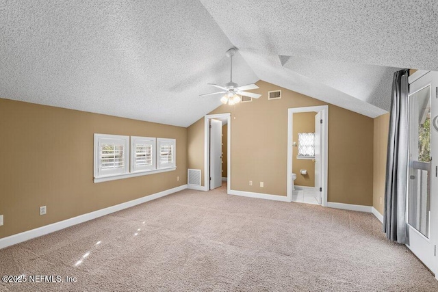 unfurnished bedroom featuring a textured ceiling, carpet flooring, lofted ceiling, and visible vents